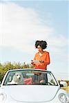 African woman reading map in convertible car