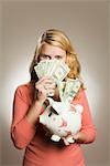 Teenage girl holding money and piggy bank