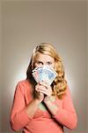 Teenage girl holding money in front of face