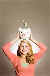 Teenage girl holding piggy bank on head