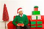 African man next to stack of Christmas gifts