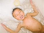 Asian boy floating in bathtub