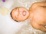 Asian boy floating in bathtub