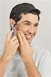 Young male adult shaving face with razor