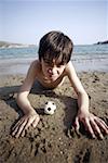 Boy with small soccer ball on beach