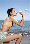 Sportlich weibliche junge Erwachsene trinken Mineralwasser am Strand