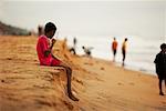 Enfant assis sur la plage, Trivandrum, Kerala, Inde