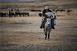 Man Holding Goat and Riding Horse Khustain Nuruu National Park, Mongolia