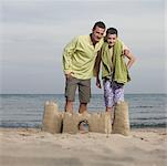 Father and son posing with sandcastle