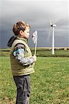 Boy blowing windmill on a wind farm