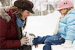 Mère aider fille Put sur patins à glace