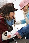 Mère aider fille Put sur patins à glace