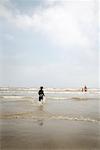 Boy Running into Water at Beach