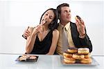 Woman Eating Sushi and Man Eating Doughnuts