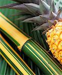 Pineapple and bamboo cane on a palm leaf