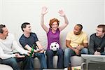 Freunde mit Fußball und Bier sitzen vor Fernseher