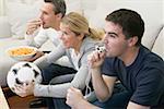 Friends watching TV with referee's whistle, football & crisps