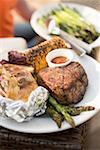 Steak de bœuf grillé avec pommes de terre au four, maïs en épi, asperges