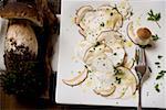 Cep carpaccio on chopping board and whole ceps