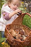 Small girl putting a cep into a basket