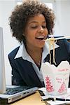 Woman in office eating Asian noodle dish