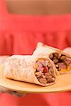 Woman holding two wraps on a plate