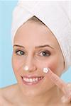 Woman with a blob of face cream on nose and finger