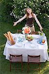 Frau präsentiert Tisch gelegt im Garten