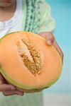 Child holding half a cantaloupe melon