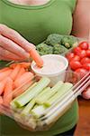 Woman holding plastic tray of vegetables and dip