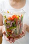 Woman holding plastic container of vegetables