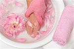 Femme laver ses pieds avec le gant exfoliant rose
