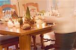 Woman bringing plates to table laid for Christmas