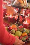 Woman placing bowl of fruit on table laid for Christmas