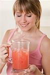 Woman holding jug of fruit juice with ice cubes