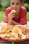 Junge Essen Nachos mit Salsa im Garten