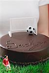 Woman holding Sacher torte with football figure & football