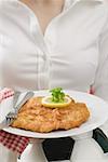 Woman holding plate of Wiener schnitzel (veal escalope) on football