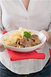 Woman holding plate of Zürcher Geschnetzeltes (veal dish) with pasta