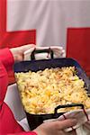 Woman serving cheese and onion pasta bake (Switzerland)