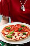 Footballeuse holding pizza tomate & mozzarella au basilic