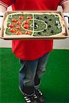 Female footballer holding spinach pizza with tomatoes & olives