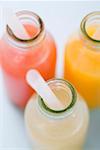 Three fruit juices in bottles with straws (overhead view)