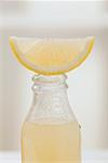 Lemon juice in bottle with fresh lemon wedge