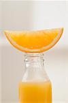 Orange juice in bottle with fresh orange wedge