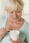 Femme manger yaourt de pot en plastique