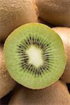 Half a kiwi fruit on several whole kiwi fruits (close-up)
