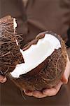 Hands holding halved coconut