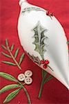 White tear-drop shaped Christmas bauble on red linen cloth