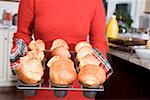 Frau hält frisch gebackenen Popovers auf einem rack